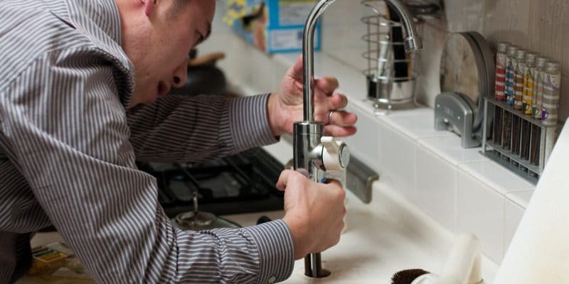 Plumber performing plumbing maintenance on a kitchen sink.