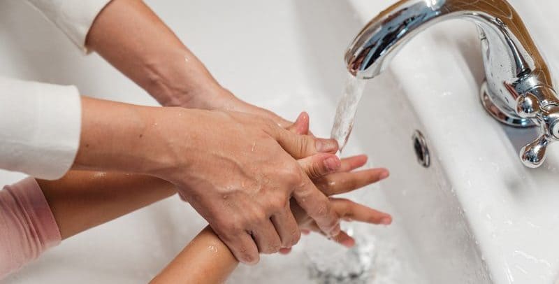 What is a tempering valve? Mother washing child's hands in warm tempered water