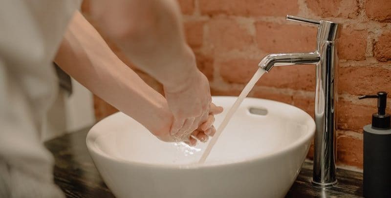 Person washing hands in hot water