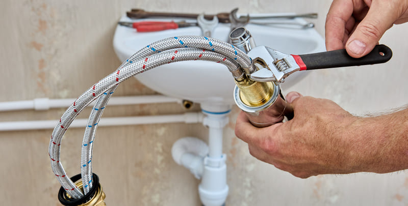 Brisbane plumber working on braided connecting hose for connecting water tap to home water supply system.