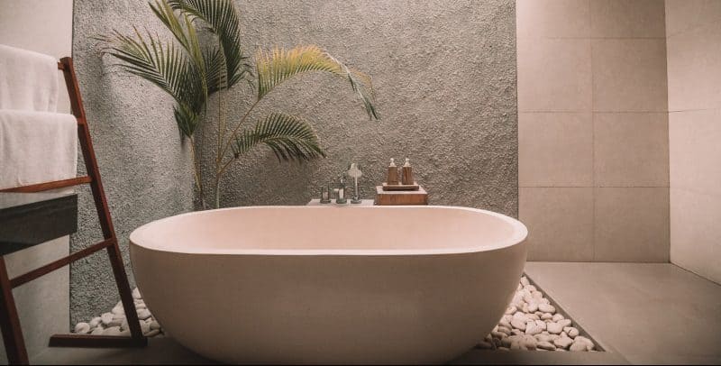 pink stone freestanding bath thub in bathroom with stone wall and pink tiles