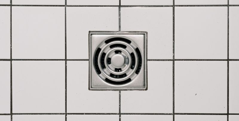 bathroom drain on white tiled floor
