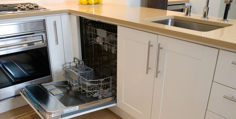 Kitchen dishwasher with door open, located under the sink and next to the stove.